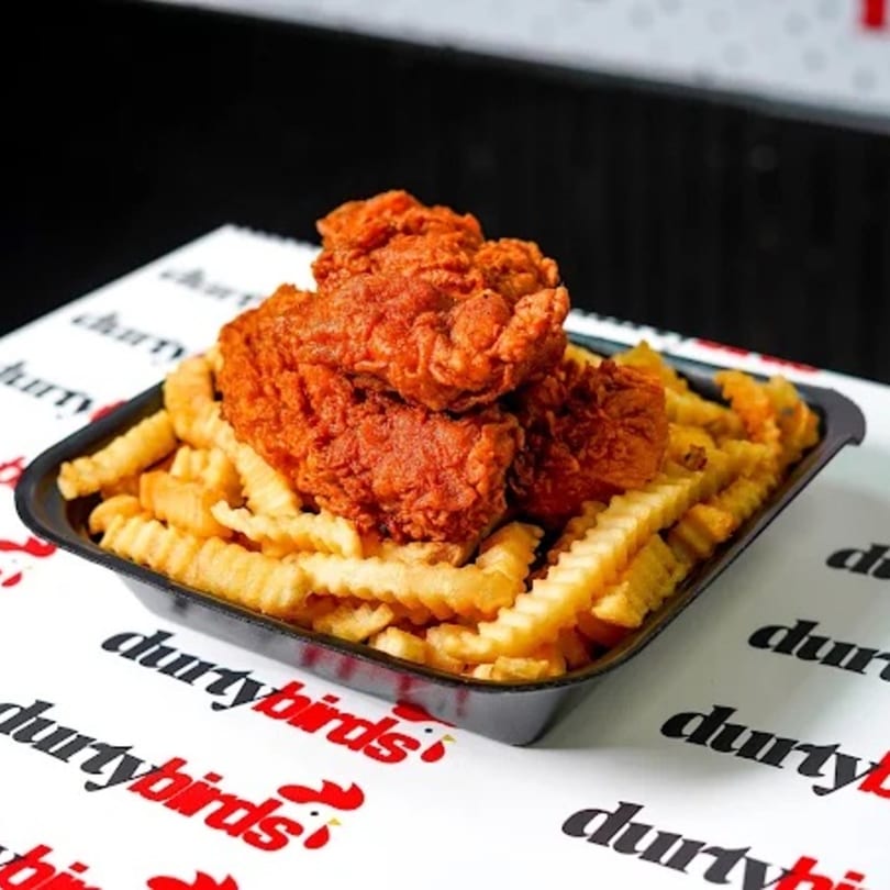 Dirty Birds' Nashville Hot chicken tenders and crinkle-cut fries in a black tray on branded paper.
