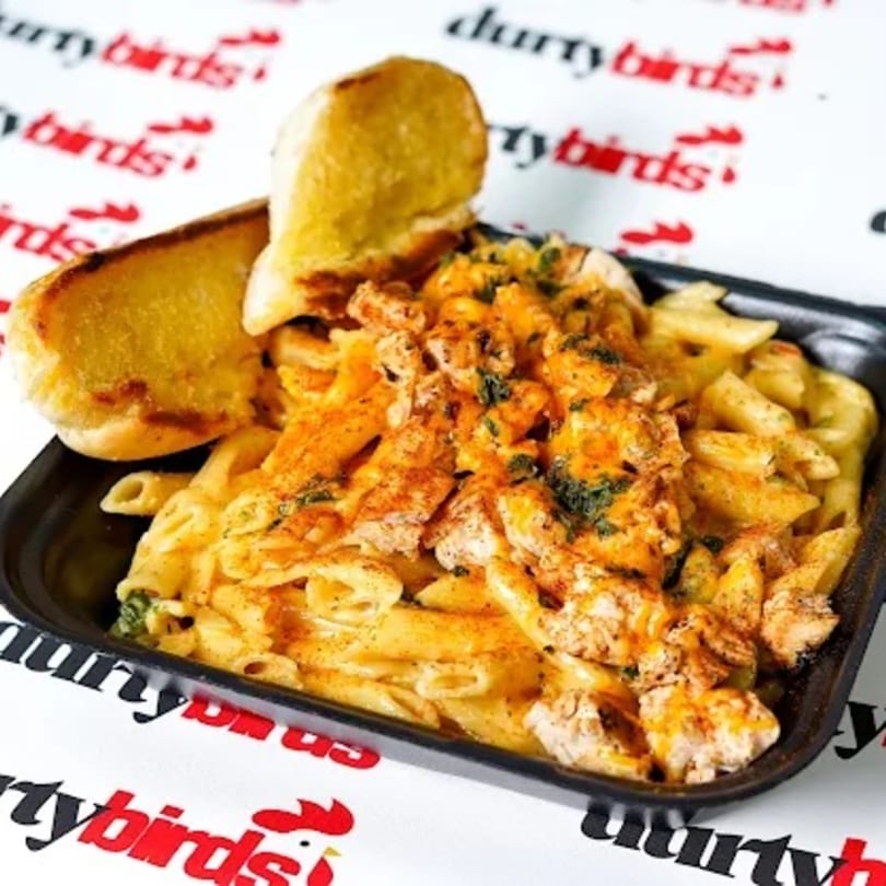Durty Birds' creamy penne pasta with chicken and garlic bread on a branded placemat.