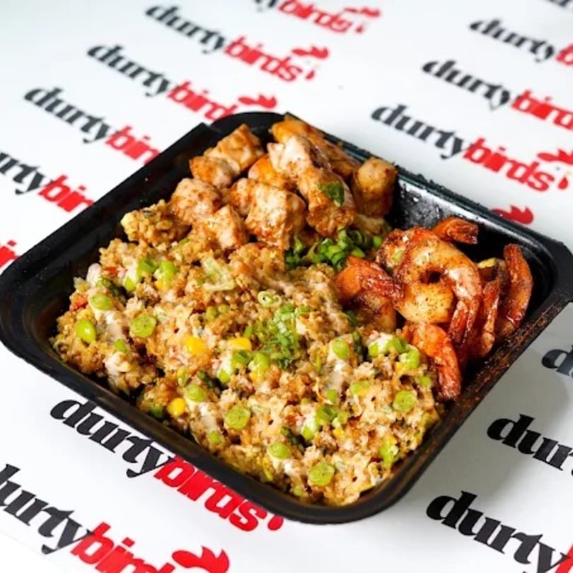 Durty Birds' fried rice with chicken and shrimp, garnished with green onions, in a black container.